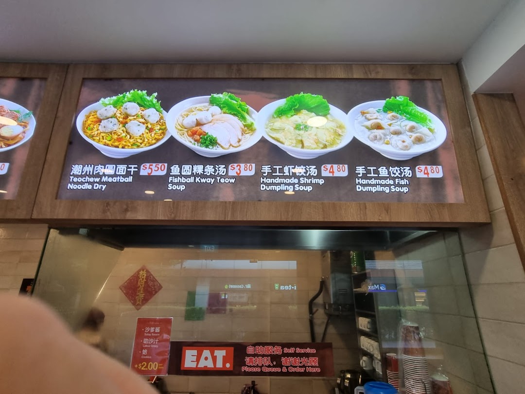 A brightly lit menu board displaying various noodle and dumpling dishes with prices at 'EAT.'