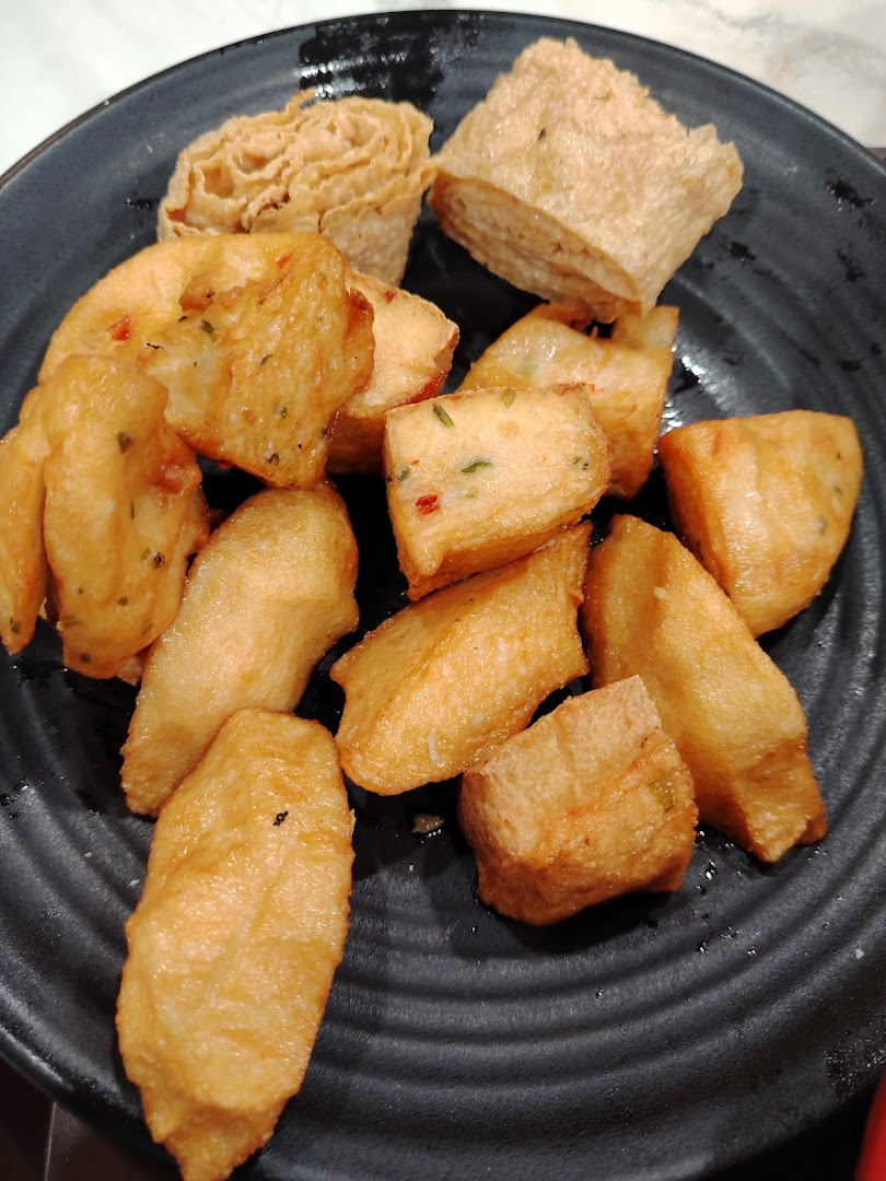 A plate filled with various golden-brown fried food items, including fish cakes and tofu skin rolls.