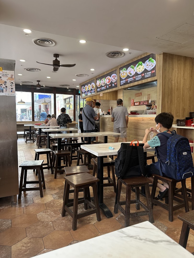 A bustling interior view of EAT, featuring customers, dining tables, and digital menu boards.