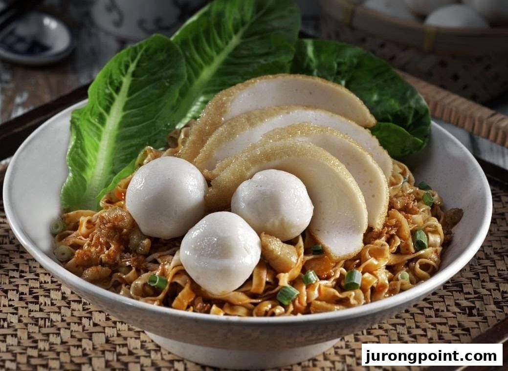 A close-up of a delicious bowl of noodles topped with fish cakes, fish balls, and fresh lettuce.