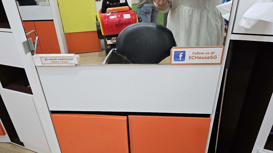 An interior view of an EC House hair salon styling station with a mirror and chair.
