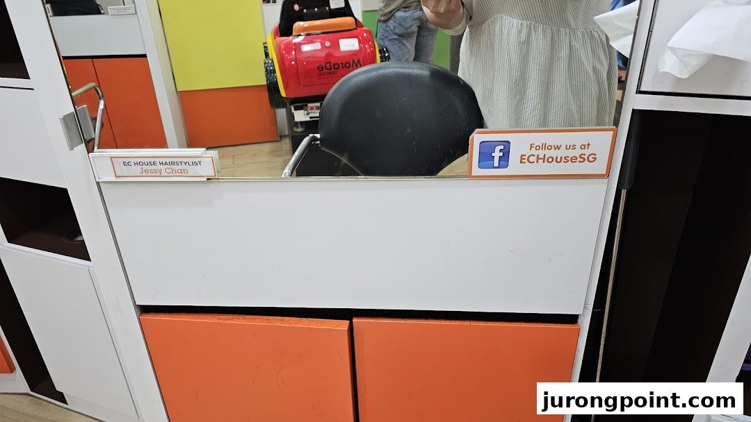 An interior view of an EC House hair salon styling station with a mirror and chair.