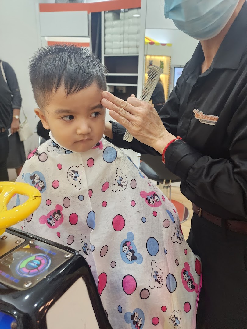 A child gets a haircut at EC House, sitting in a fun car-shaped chair.