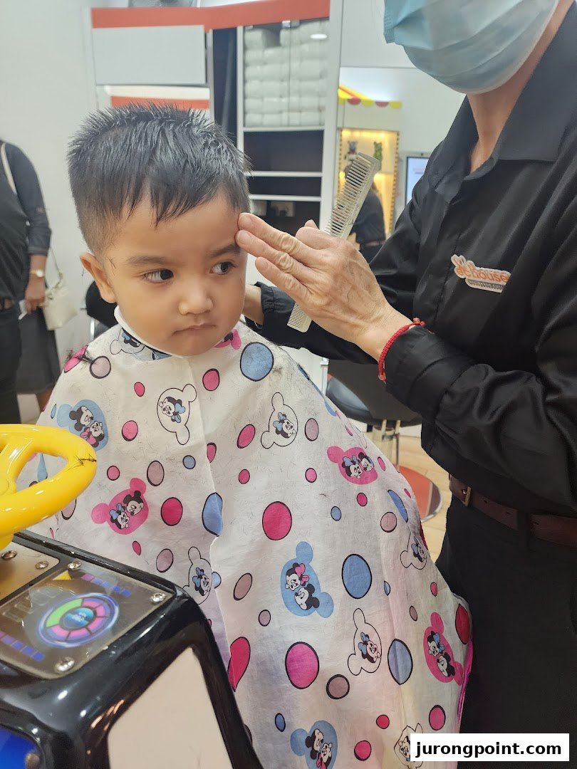 A child gets a haircut at EC House, sitting in a fun car-shaped chair.