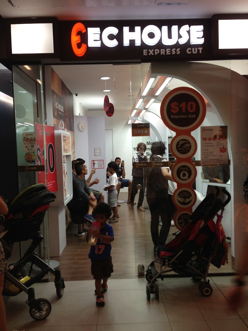 The storefront of EC House Express Cut, a hair salon, with customers inside and a child walking by.