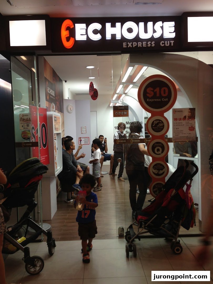 The storefront of EC House Express Cut, a hair salon, with customers inside and a child walking by.