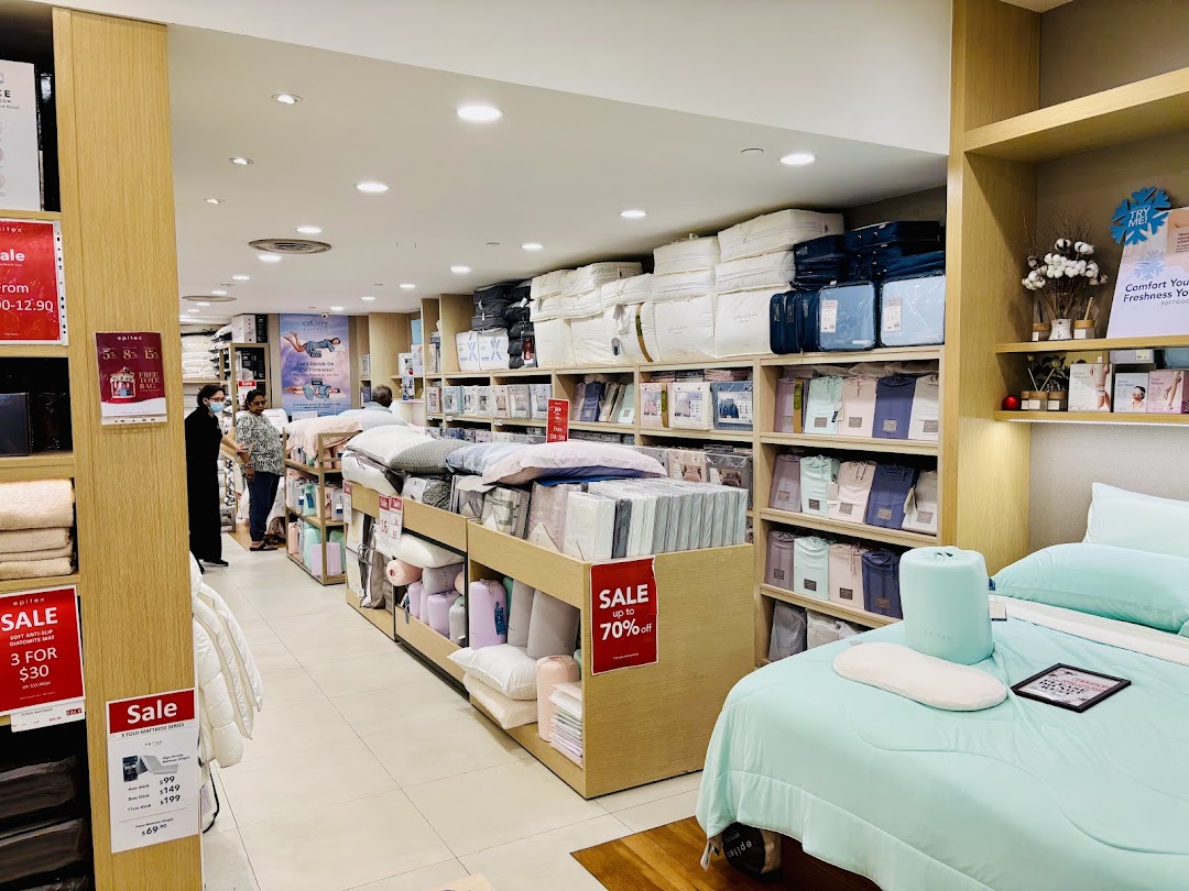 Interior view of Epitex store showcasing bedding, pillows, and home textiles with customers browsing.