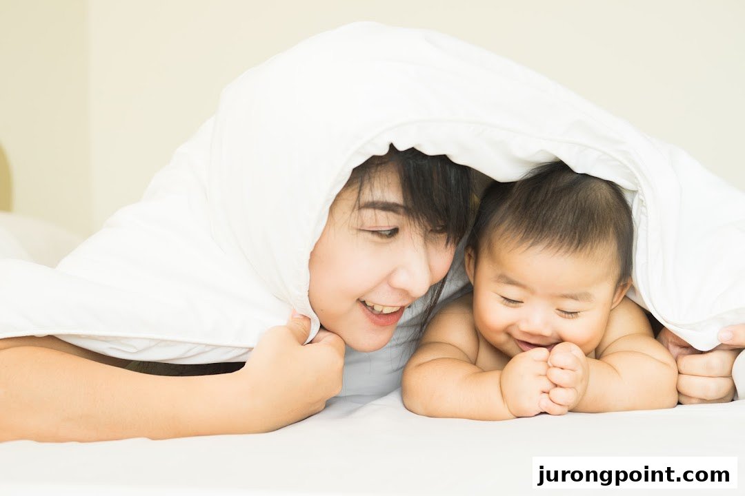 A mother and baby smiling happily under a soft white blanket, illustrating comfort and warmth.