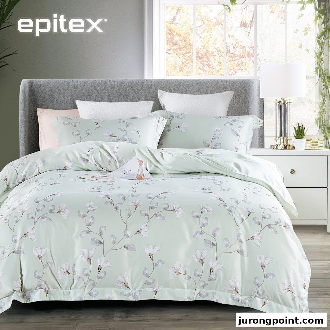 A bed styled with light green floral bedding, a bedside table, and a window view.