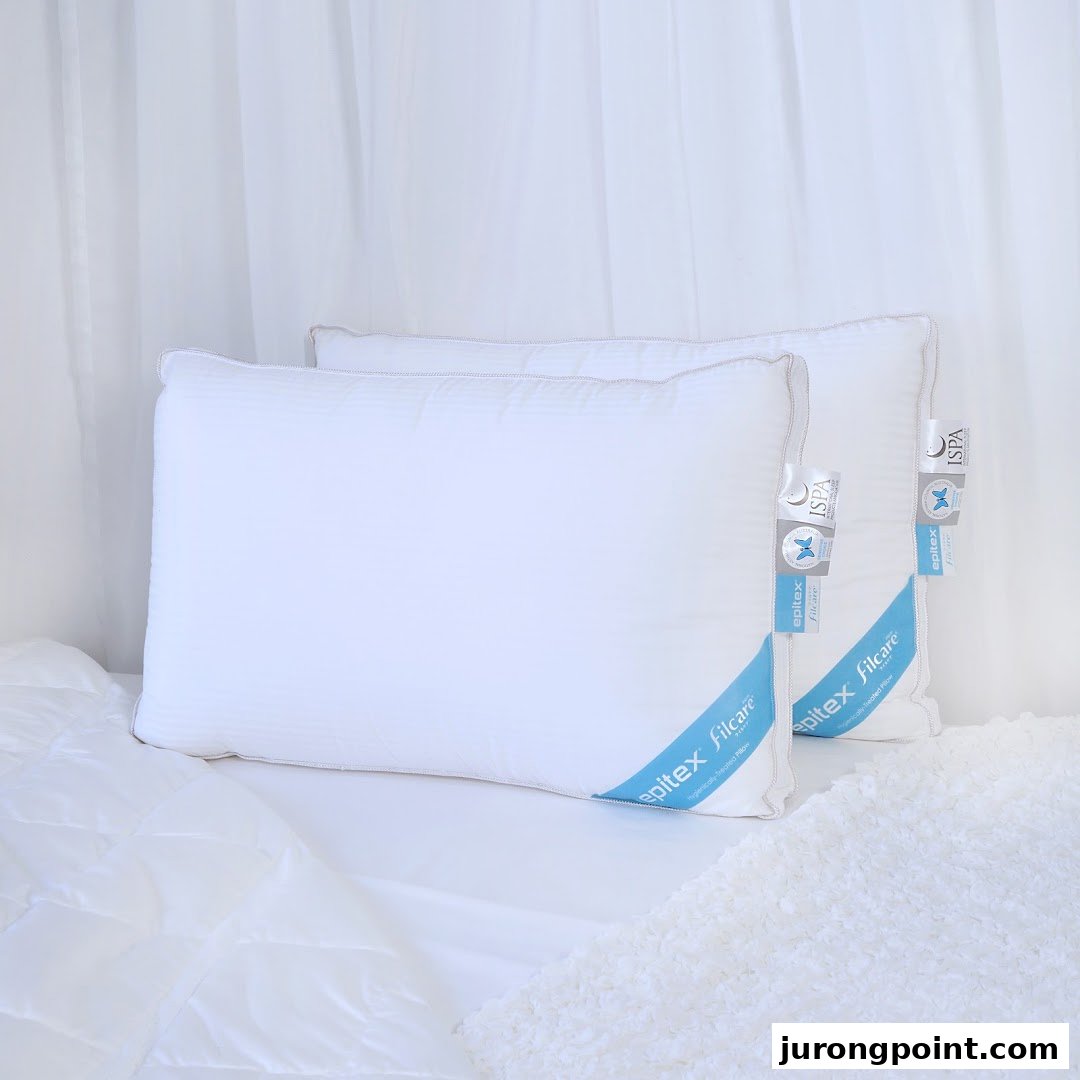 Two white Epitex Filcare pillows displayed on a bed with white bedding.