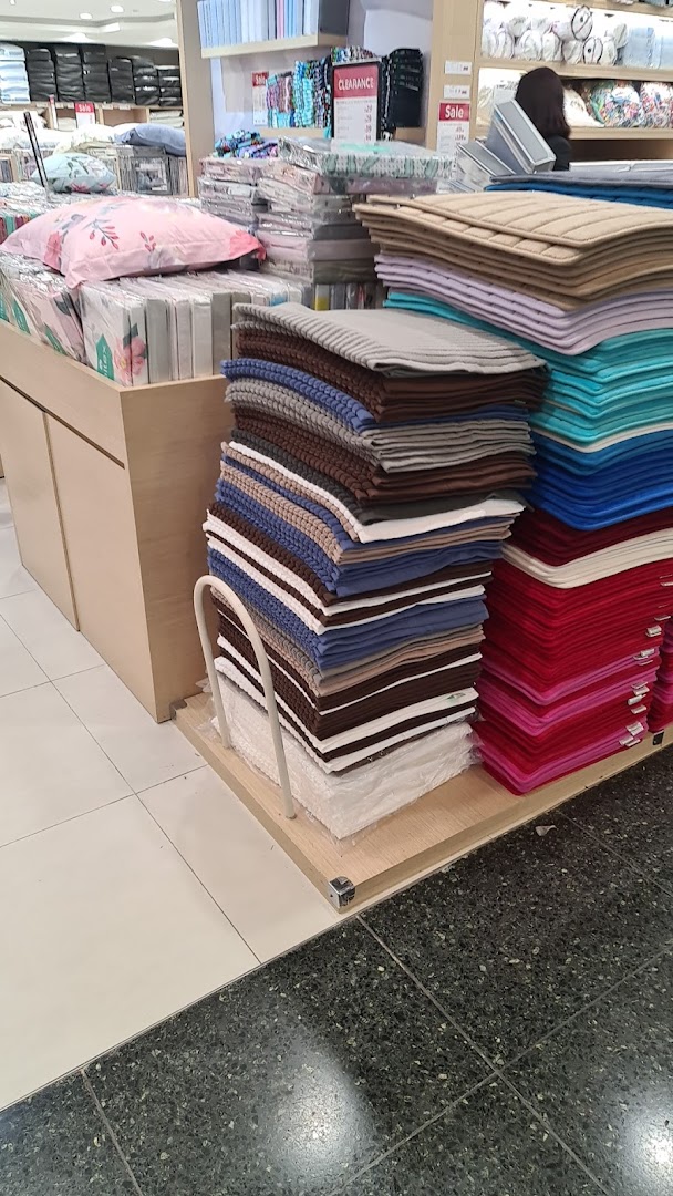 An interior shot of Epitex, showcasing stacks of colorful bath mats and other home textile products.