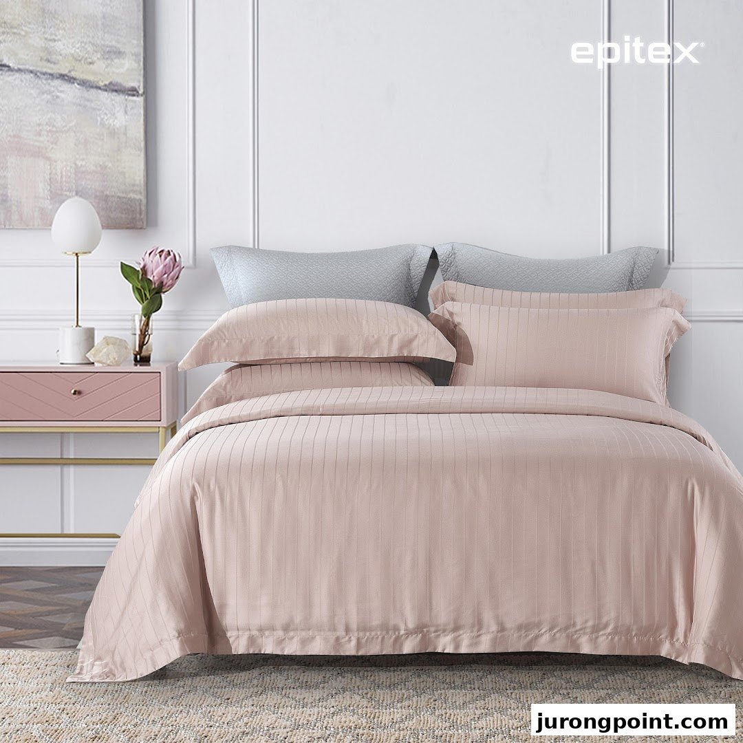 A beautifully styled bed featuring soft pink striped bedding from Epitex, with elegant bedroom decor.