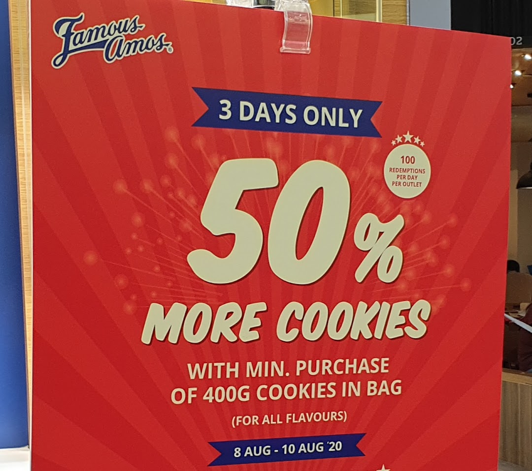 A vibrant red Famous Amos promotional poster advertising 50% more cookies with purchase for a limited time.