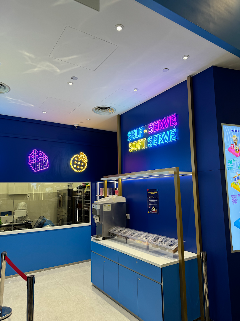 An interior view of Famous Amos featuring a self-serve soft serve station and a visible baking area.