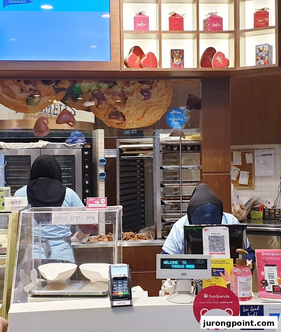 An interior view of Famous Amos, showing staff preparing cookies and the counter area.