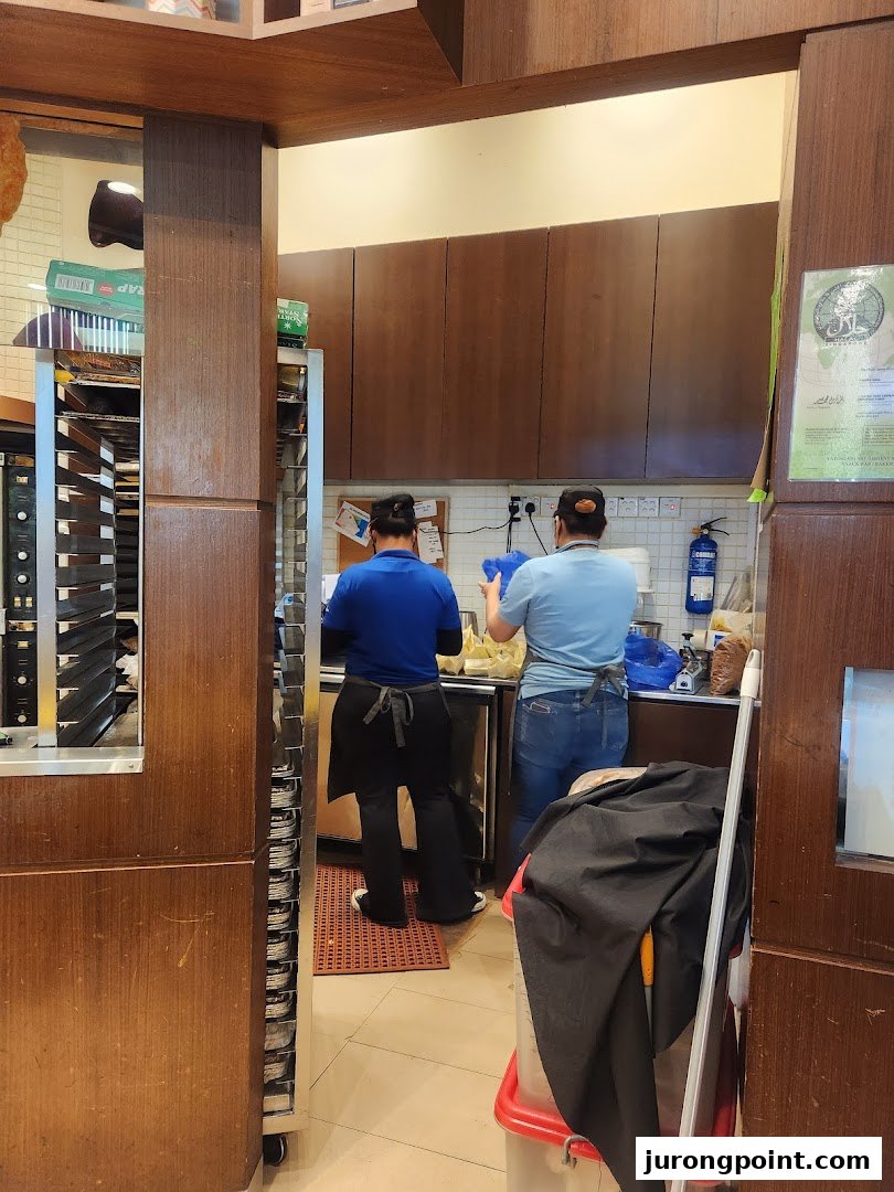 Two staff members are seen preparing products in the kitchen area of Famous Amos.
