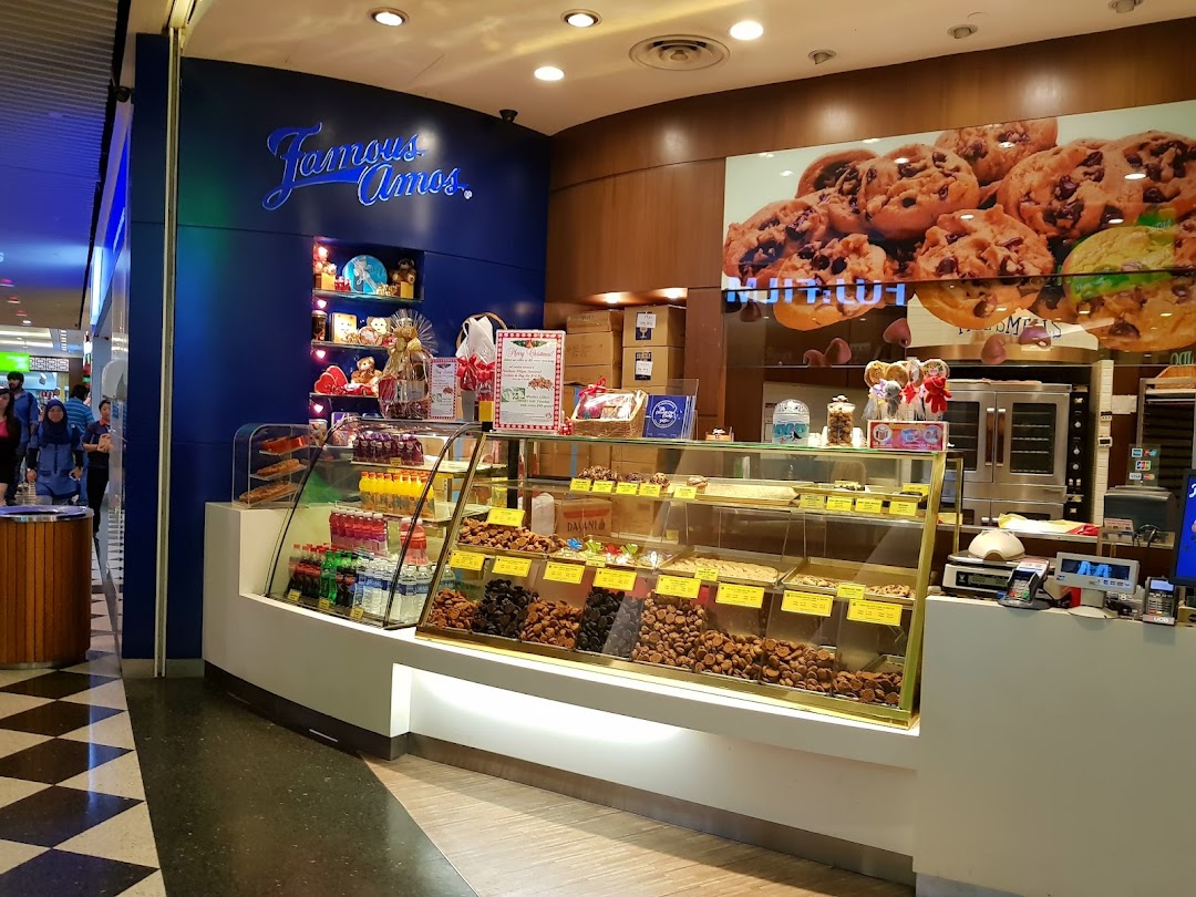 A vibrant Famous Amos cookie shop entrance showcasing fresh cookies and festive displays.