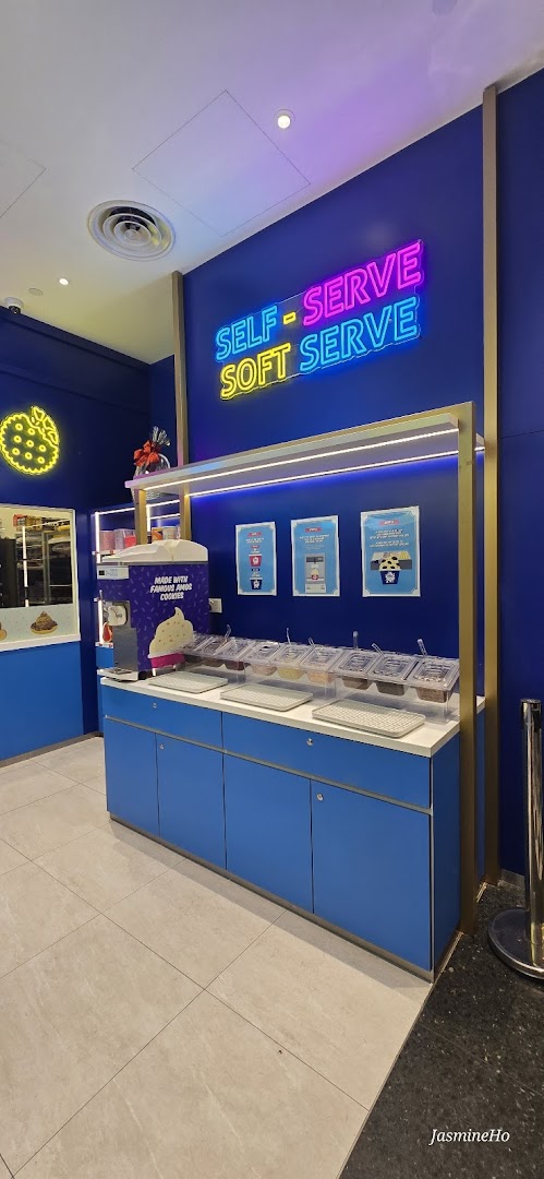 A vibrant Famous Amos shop interior featuring a self-serve soft serve station with various toppings.