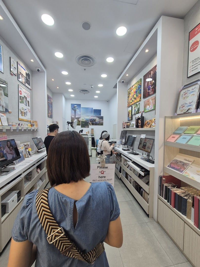 Interior view of FotoHub, showcasing photo printing stations, personalized products, and customers browsing.