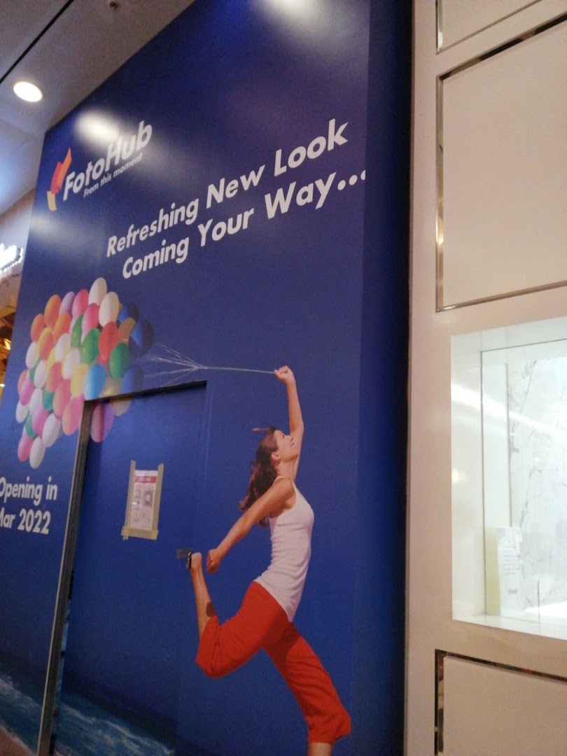 A FotoHub shop front with a large banner announcing a 'Refreshing New Look' and March 2022 opening.