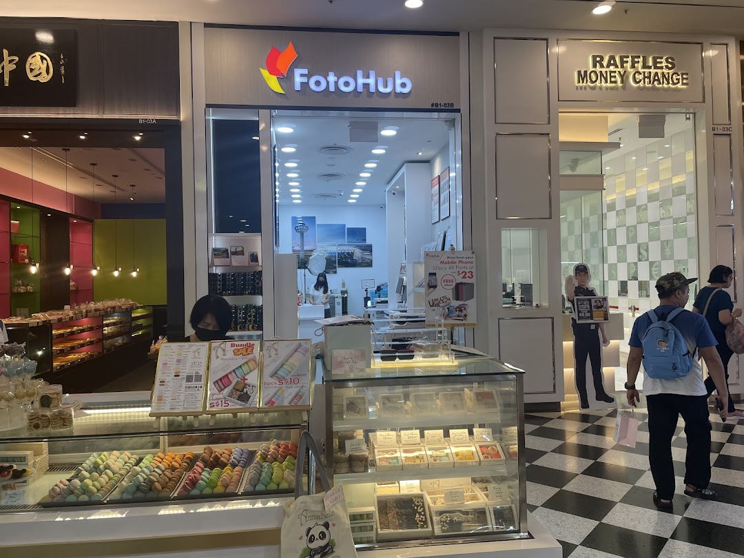 The storefront of FotoHub, a photo printing and mobile accessories shop, within a bustling mall.