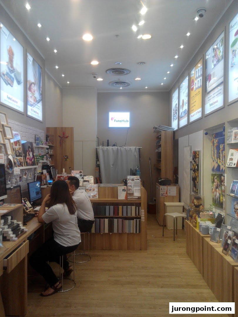 Interior view of FotoHub, a photo printing shop, with staff assisting customers.