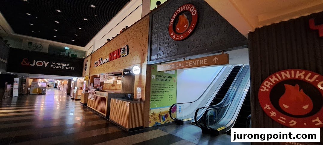 A mall corridor featuring Japanese food stalls and a directional sign to the Medical Centre, including Fullerton Health.