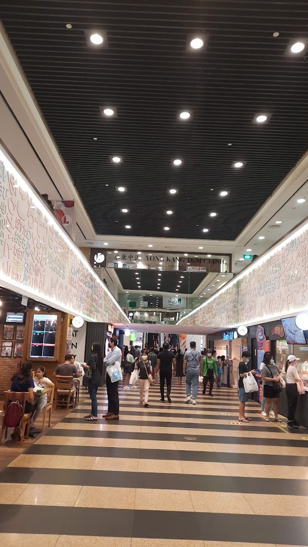 A bustling mall corridor with various shops, people, and bright lighting.