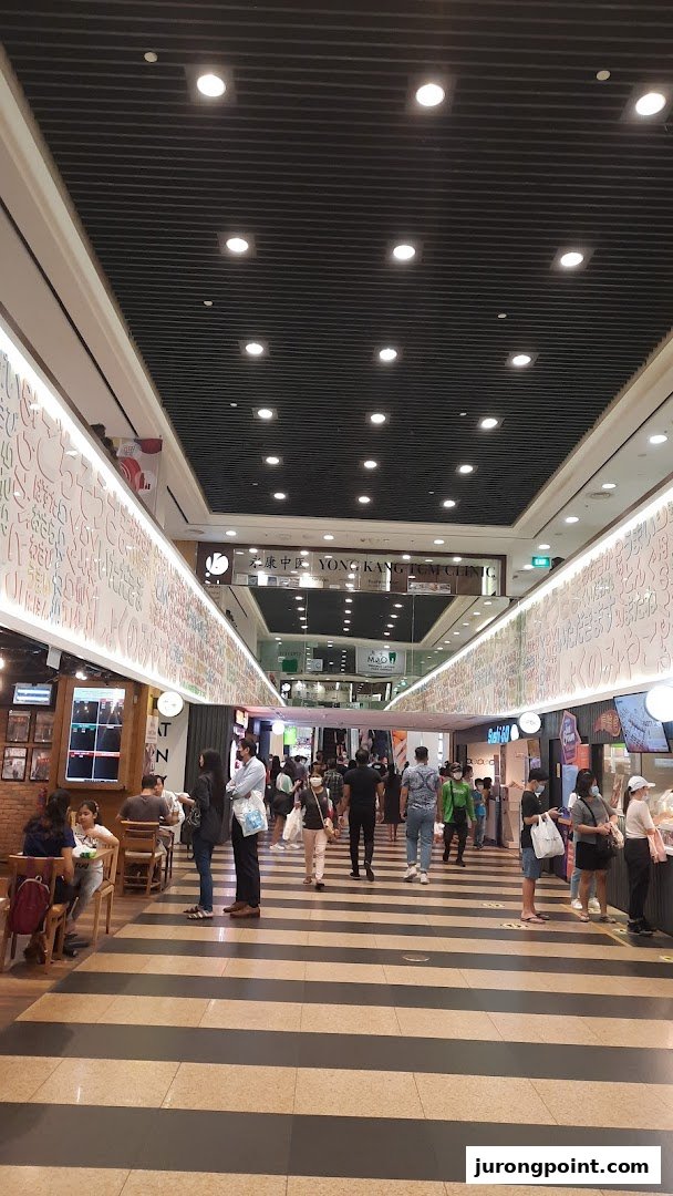 A bustling mall corridor with various shops, people, and bright lighting.