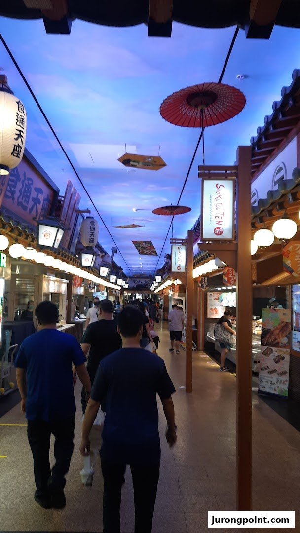 A vibrant Japanese-themed food street bustling with visitors exploring various eateries.