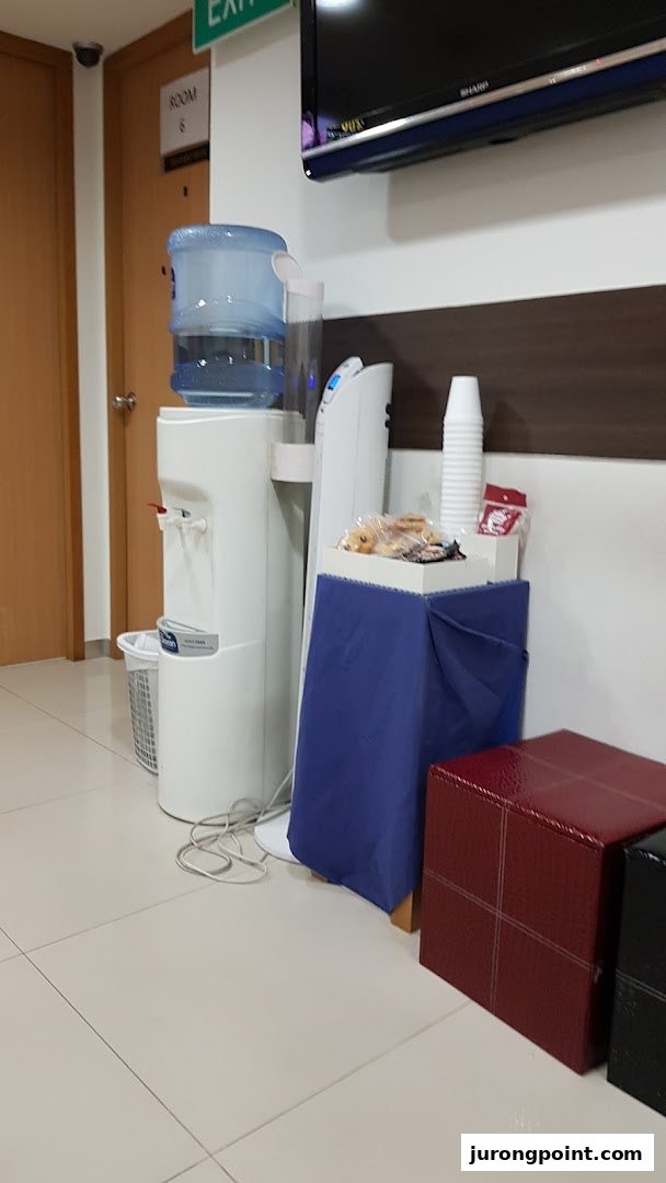 A waiting area with a water dispenser, snacks, and seating at Fullerton Health.
