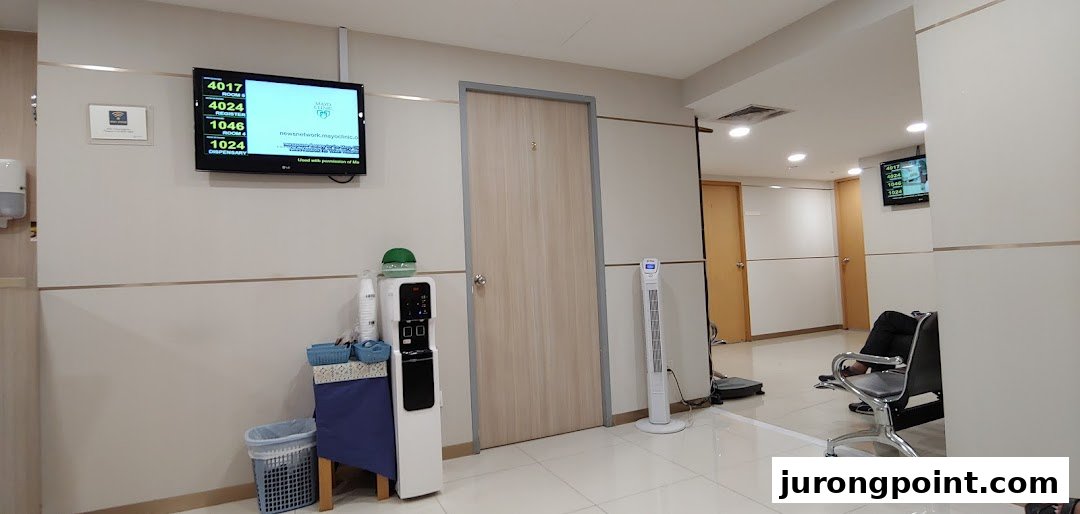 A clean and modern waiting area at Fullerton Health, featuring a queue display and water dispenser.