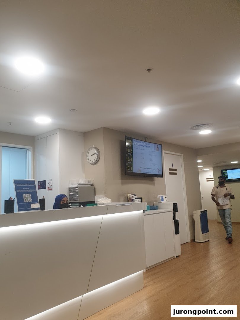A modern reception area at Fullerton Health with a staff member and digital queue display.