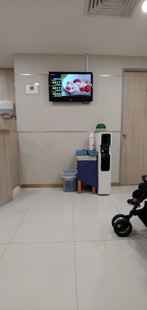 A clean and comfortable waiting area at Fullerton Health, featuring a queue number display and water dispenser.