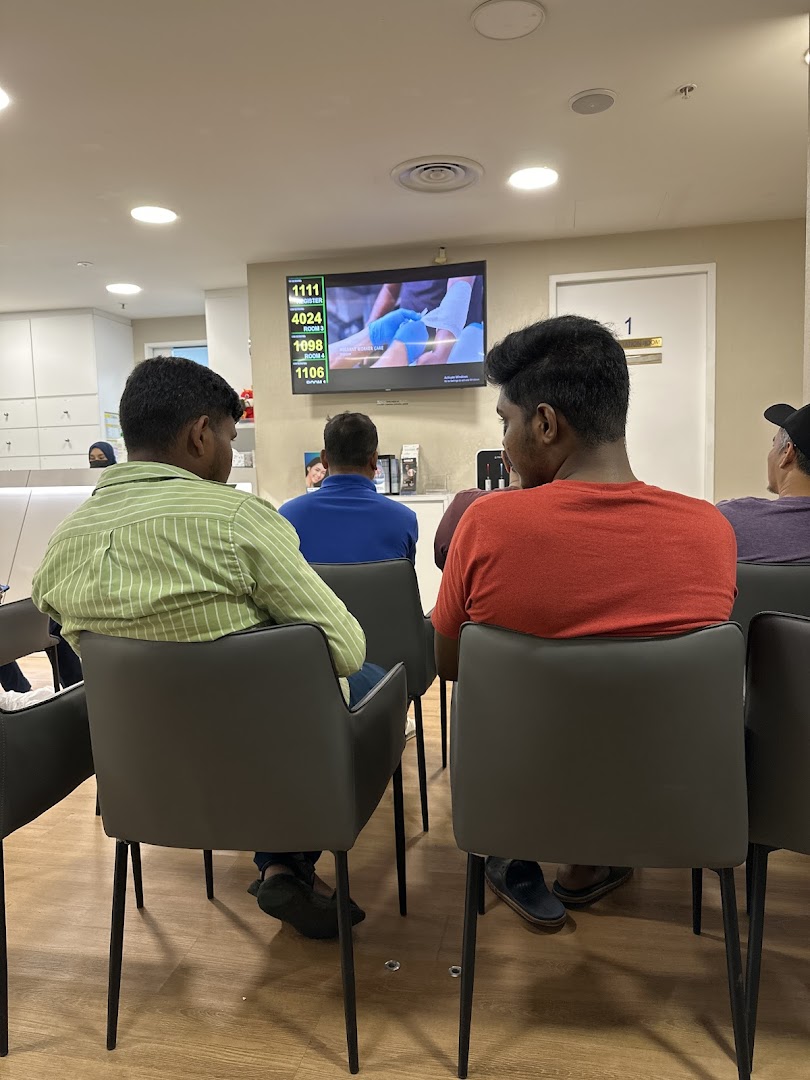 Patients comfortably wait in the modern reception area of Fullerton Health, featuring a digital queue display.