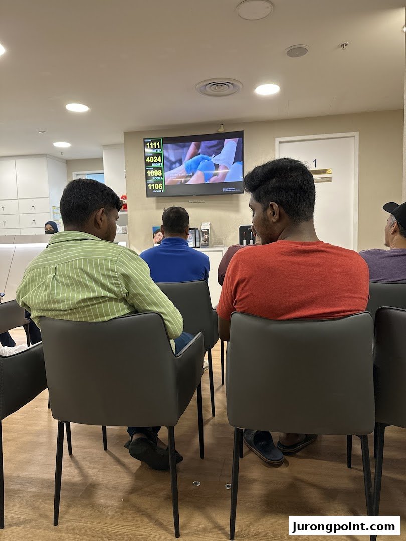 Patients comfortably wait in the modern reception area of Fullerton Health, featuring a digital queue display.