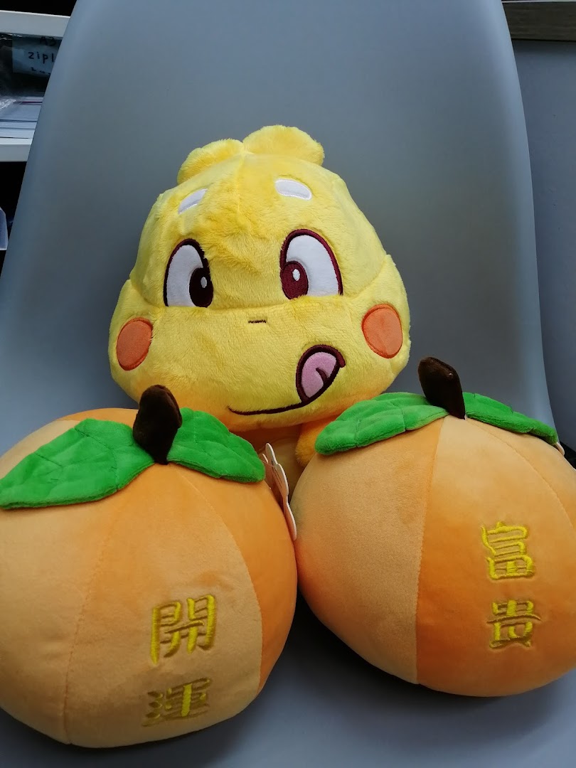 Close-up of colorful plush toys, including a yellow character and two orange fruit-shaped items.