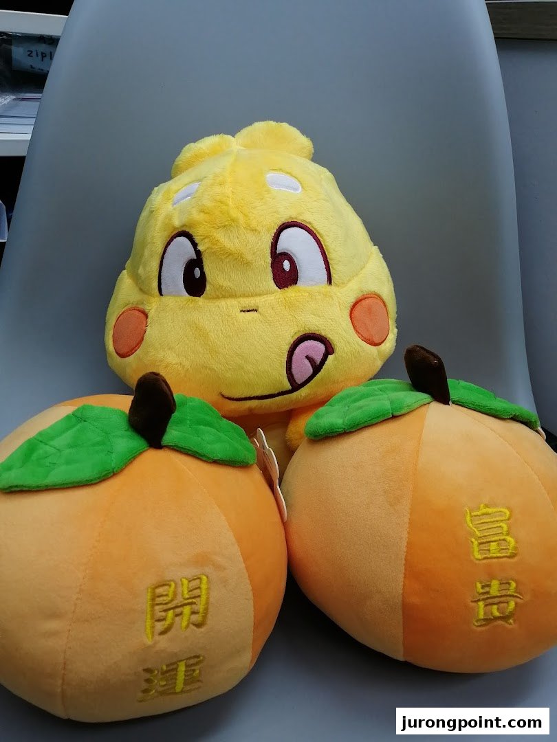 Close-up of colorful plush toys, including a yellow character and two orange fruit-shaped items.