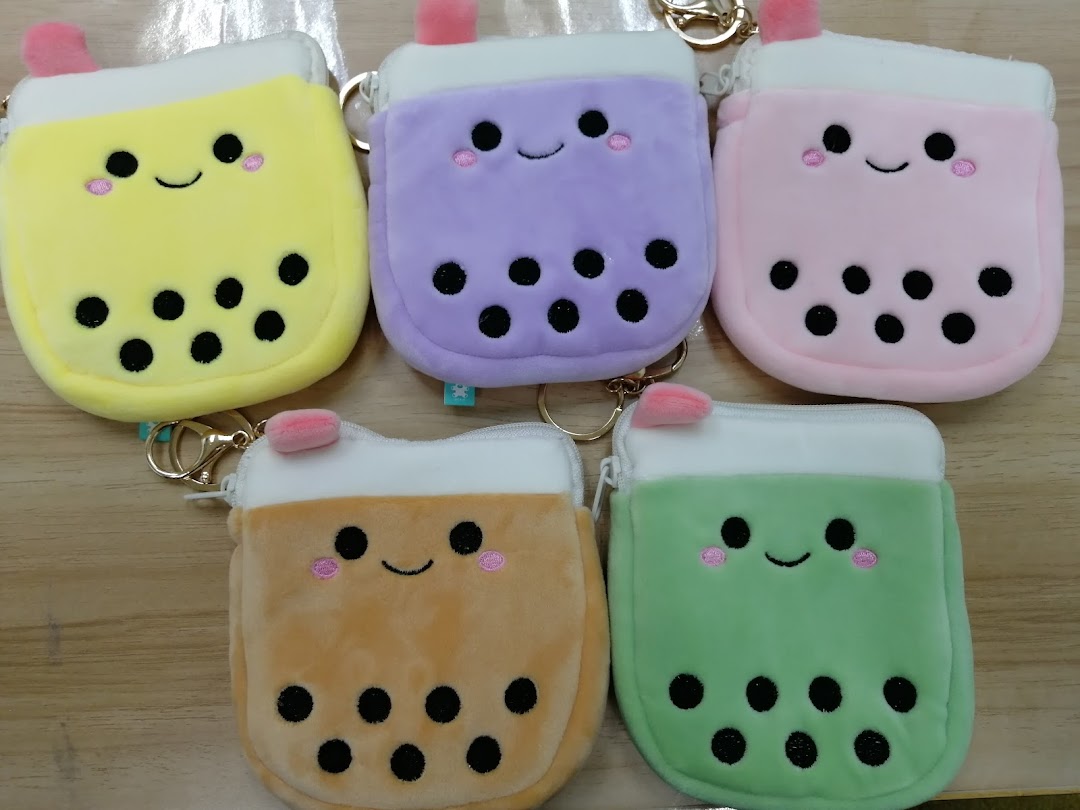 A vibrant collection of five smiling bubble tea plush coin purses or keychains in various colors.