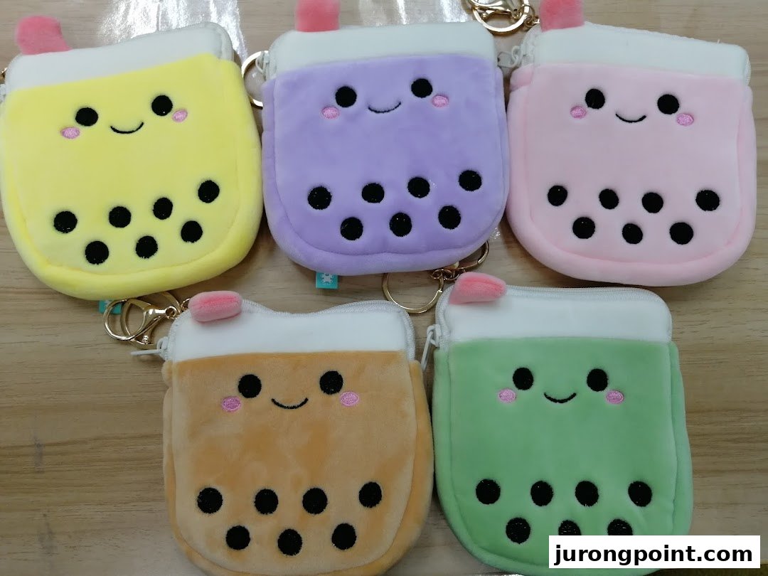 A vibrant collection of five smiling bubble tea plush coin purses or keychains in various colors.