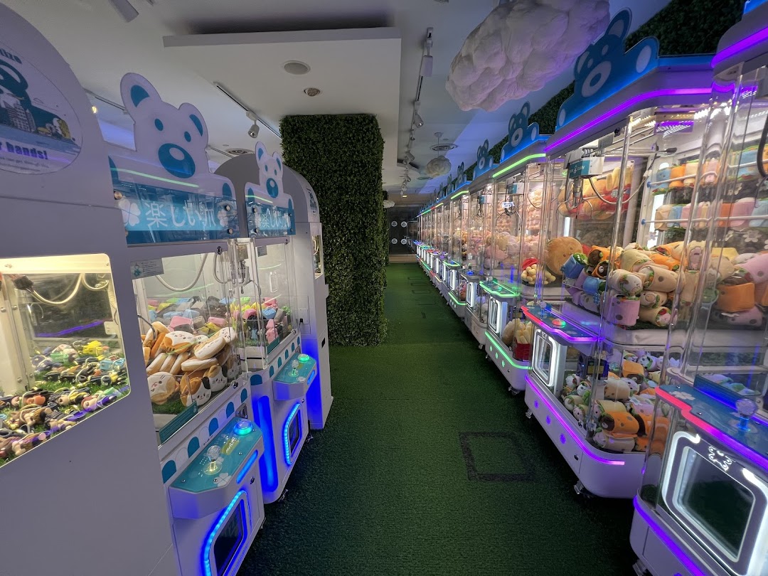 A vibrant interior view of Fun Claw, showcasing a long aisle of brightly lit claw machines filled with prizes.