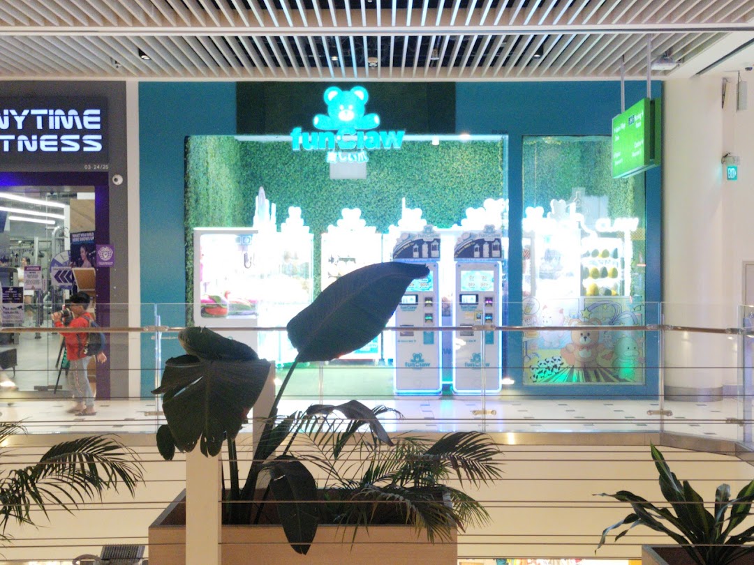 The brightly lit storefront of Fun Claw, featuring claw machines and plush toys, viewed from a mall balcony.