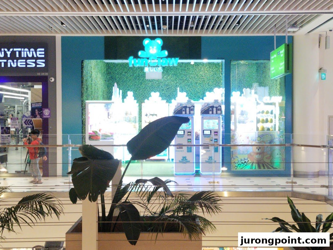 The brightly lit storefront of Fun Claw, featuring claw machines and plush toys, viewed from a mall balcony.
