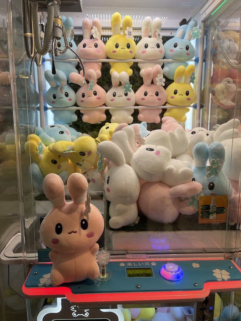 A vibrant claw machine filled with an assortment of cute, pastel-colored bunny plush toys.