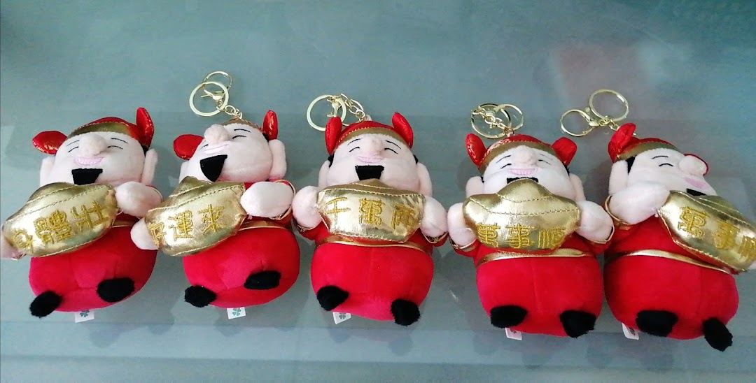 Five plush keychains depicting smiling figures in red holding golden ingots, likely claw machine prizes.