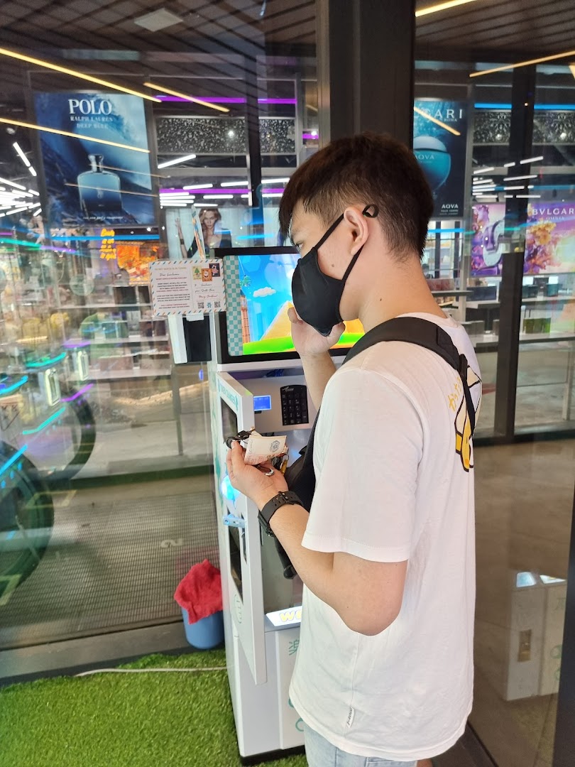 A masked person interacts with a claw machine inside Fun Claw, holding cash.