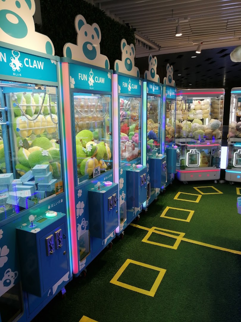 A vibrant row of Fun Claw arcade machines filled with plush toys and prizes on green turf.