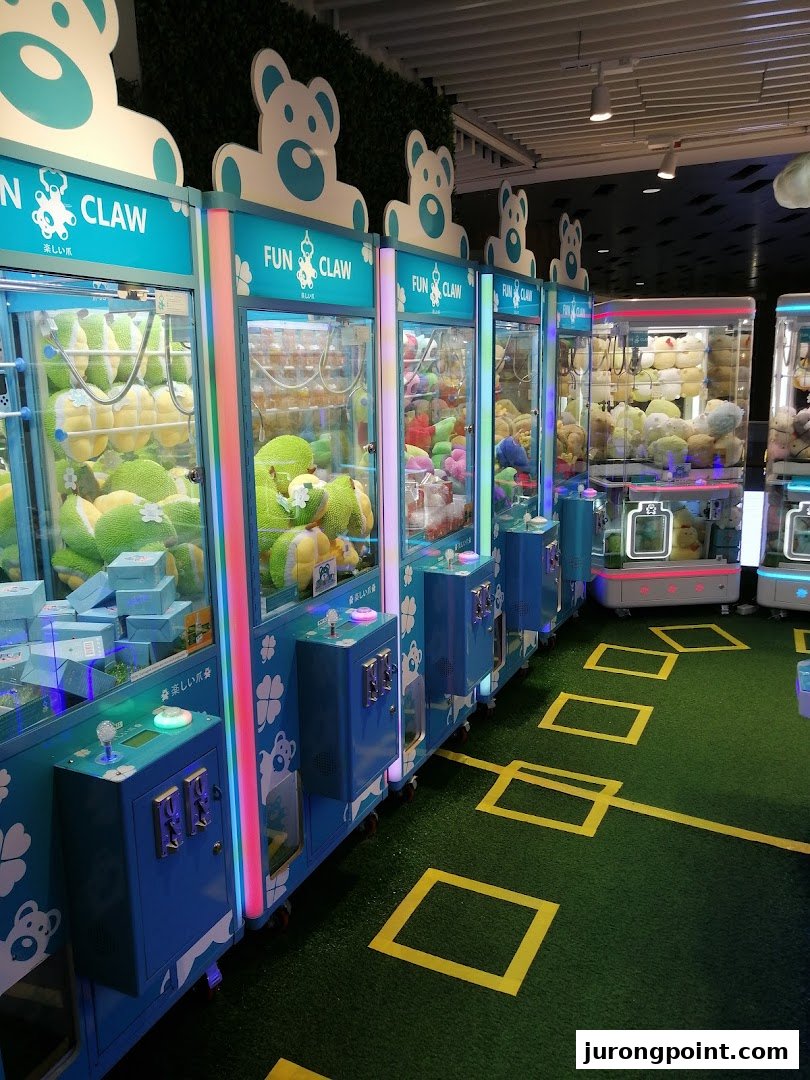 A vibrant row of Fun Claw arcade machines filled with plush toys and prizes on green turf.