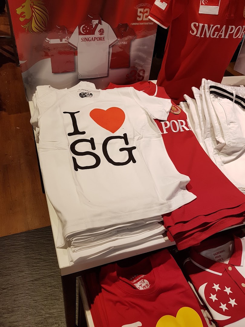 A display of Singapore-themed apparel, including 'I ❤️ SG' t-shirts and red polo shirts, inside Giordano.
