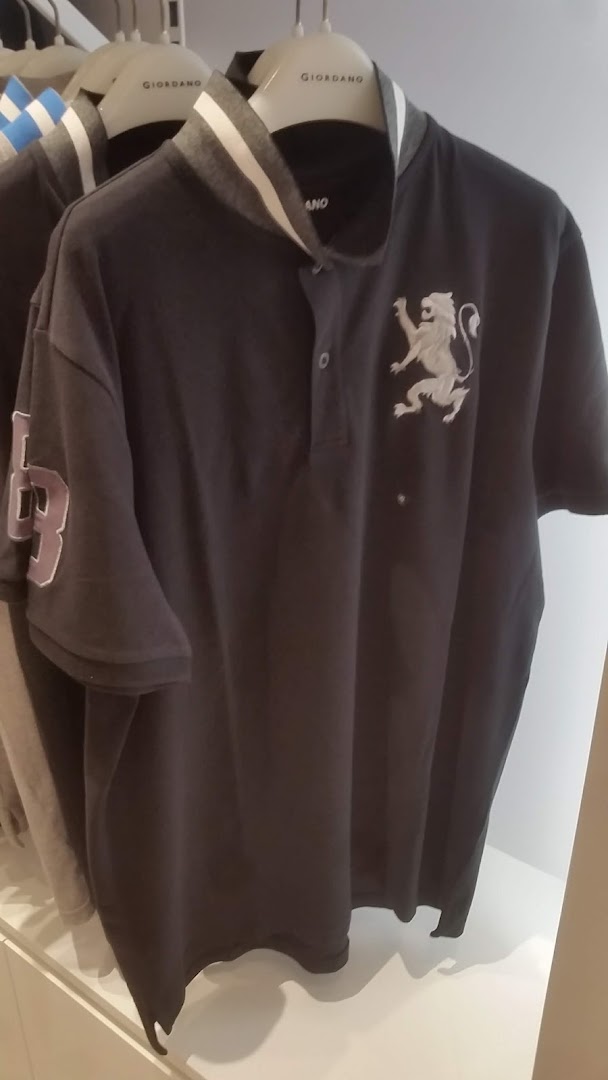 A dark grey polo shirt with a white lion emblem and striped collar hangs in a Giordano store.